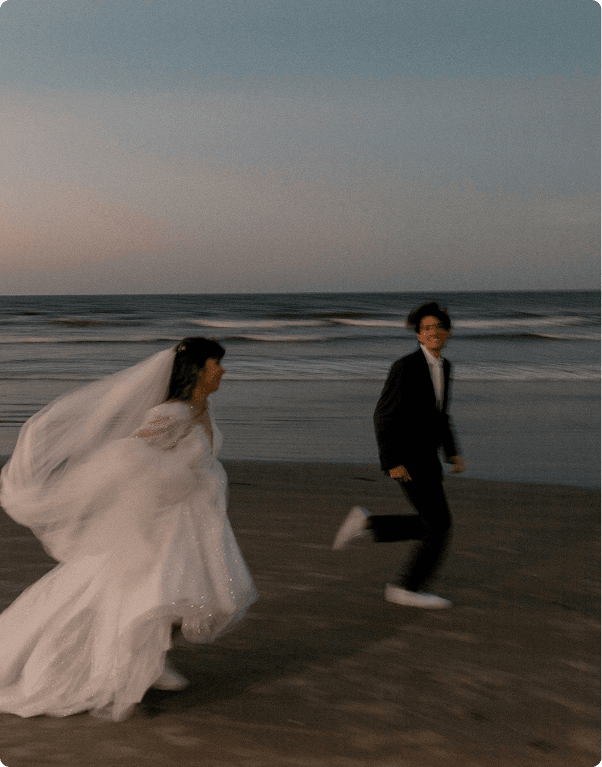 wedding couple runs along a beach at sunset