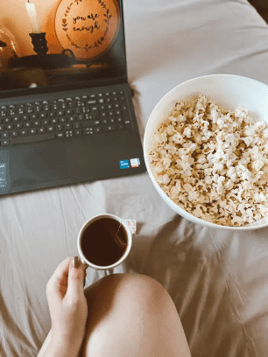 a movie on a laptop with a bowl of popcorn